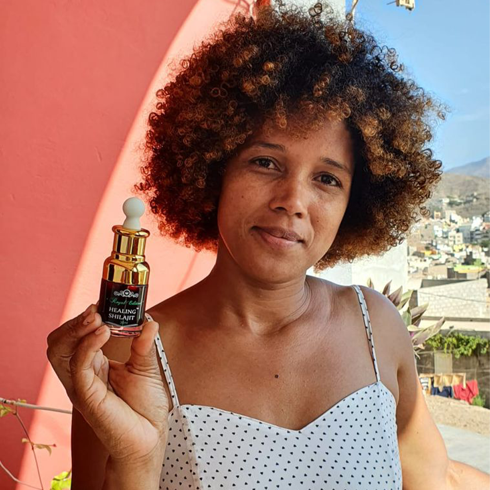 A woman is holding Shilajit drops in her hand.